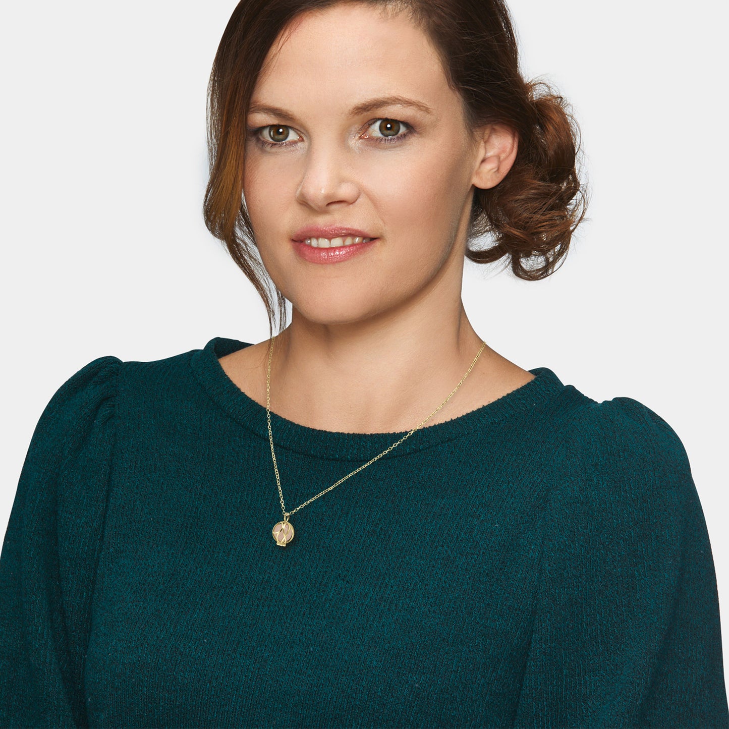 Frau mit braunen Haaren und grünem Pullover trägt die Engelsrufer-Kette Powerful Stone Paradise in Gold mit Rosenquarz-Kraftperle.